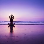 Woman practicing yoga on the beach