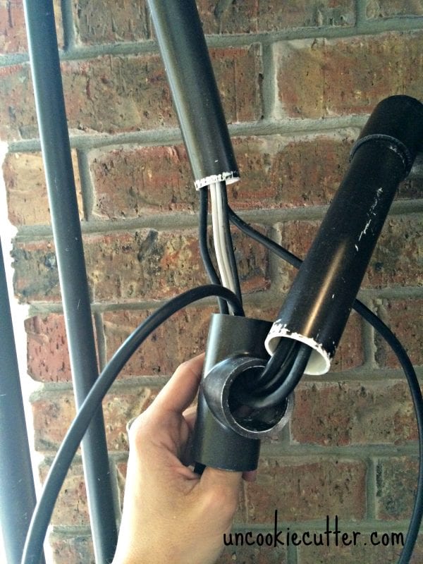 hide television cords in faux pipe shelving as entertainment center (UncookieCutter)