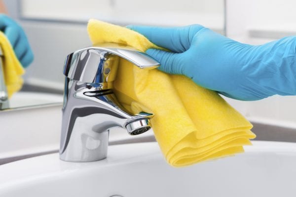 Woman doing chores in bathroom, cleaning tap