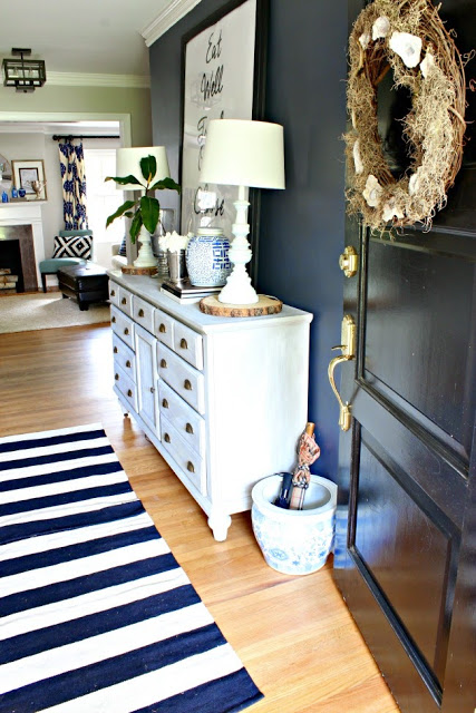 The navy wall in this foyer is gorgeous! And the wood slice under the lamps is a fun rustic touch to a more traditional space. | 100+ Beautiful Mudrooms and Entryways at Remodelaholic.com
