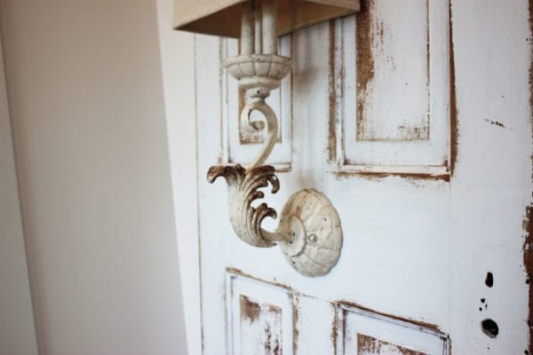 Wall sconce mounted on antique door used as bedside lighting, by Simple Nature Decor featured on @Remodelaholic