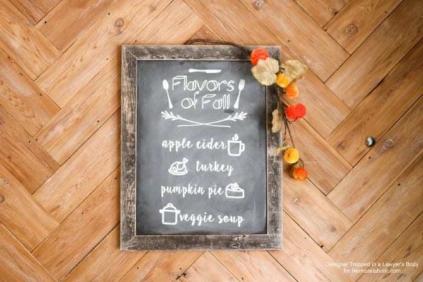 Herringbone Wooden Floor With A Reusable Faux Chalkboard Sign With Flavors Of Fall On It Showing Apple Cider, Turkey, Pumplin Pie And Veggie Soup